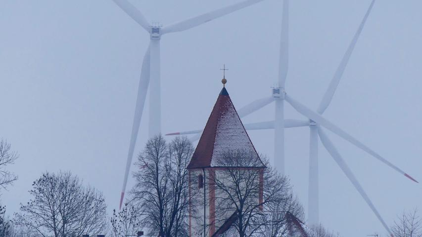 Die Kirche St. Clemens in Biburg ist scheinbar von Windrädern umringt.
