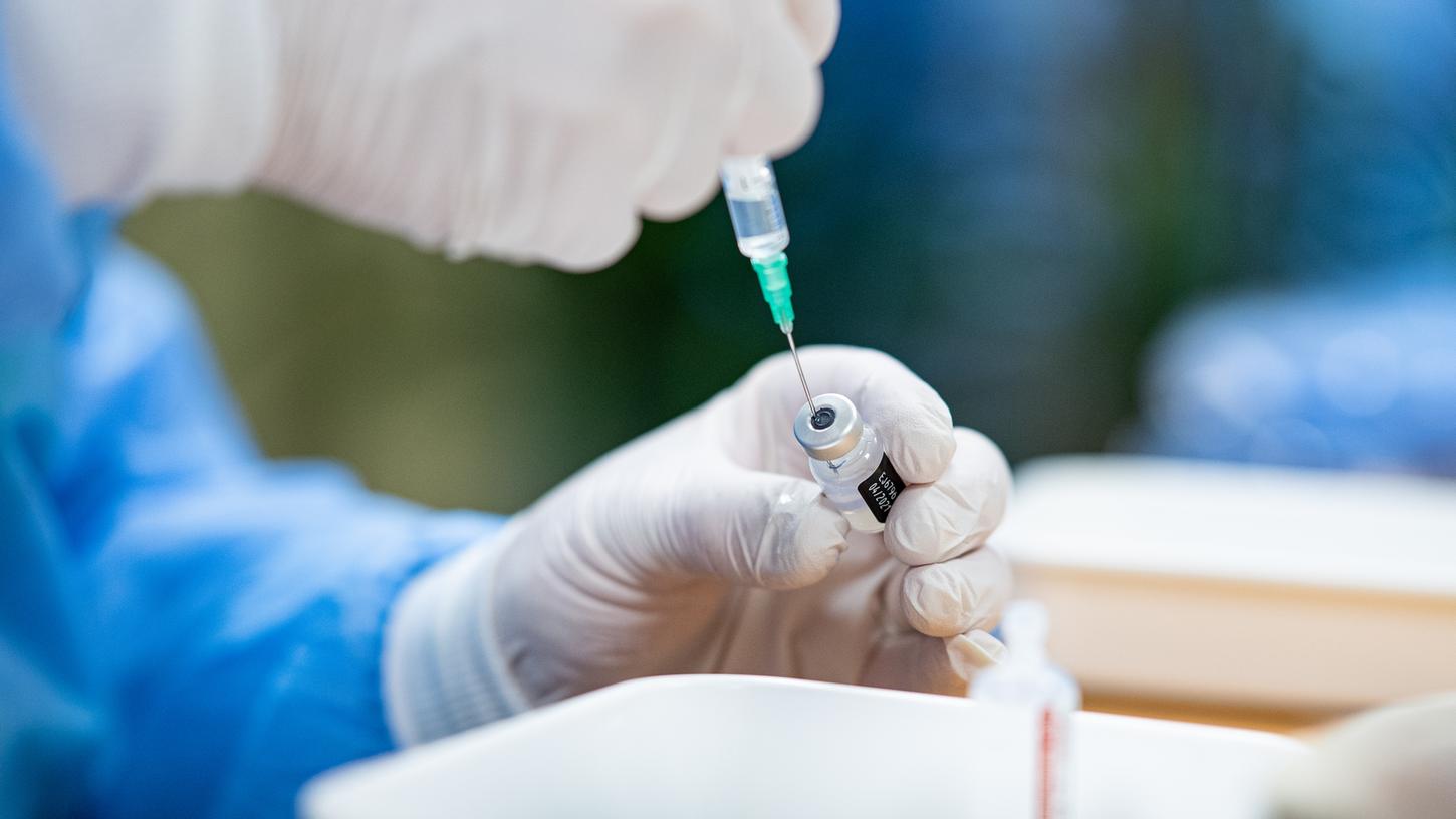 Ein Infektiologe zieht in einem Seniorenheim eine Spritze mit Impfstoff gegen das Coronavirus auf. 