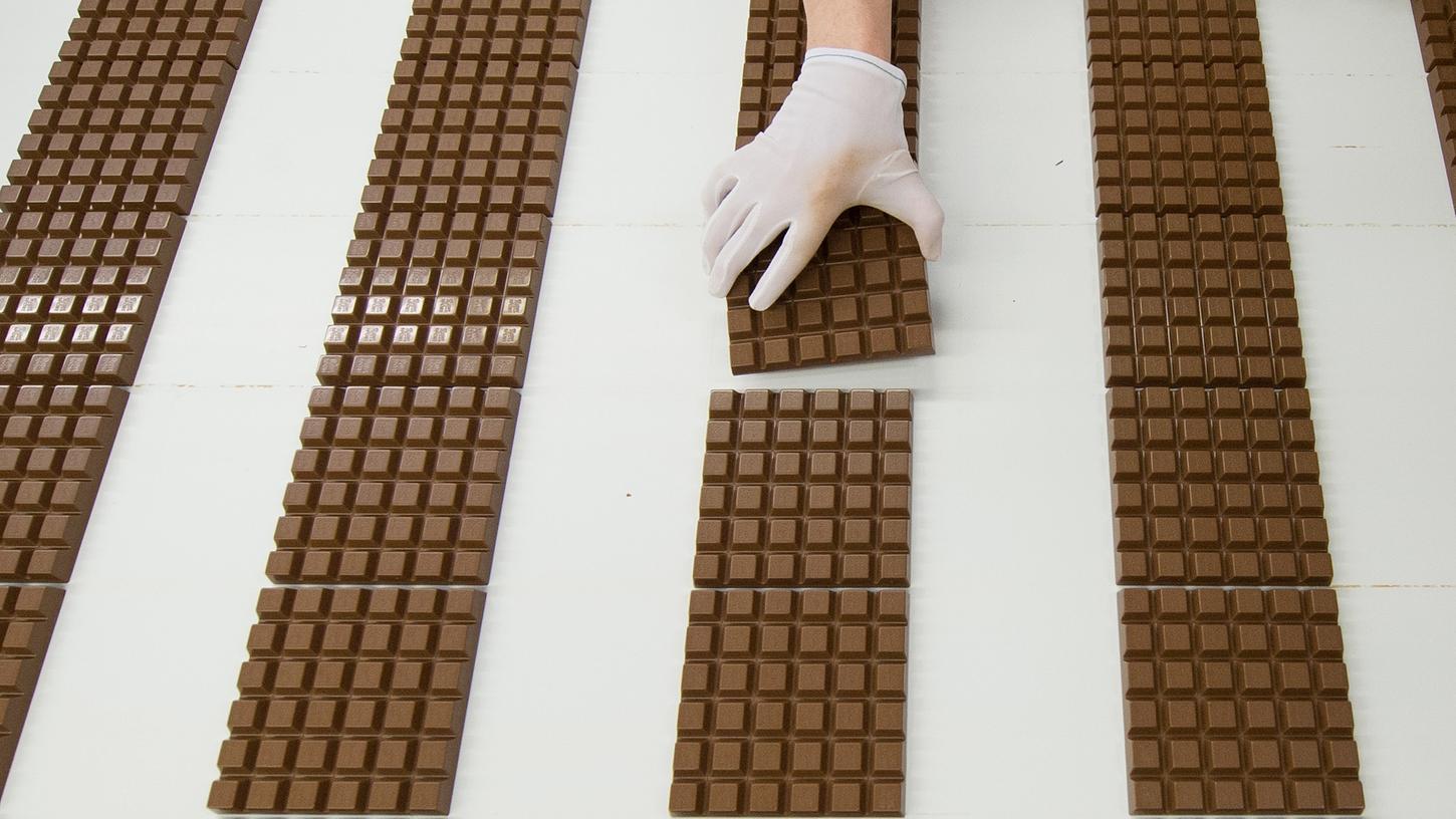 Eine Mitarbeiterin des Schokoladenherstellers Ritter kontrolliert in der Produktion Schokoladentafeln.