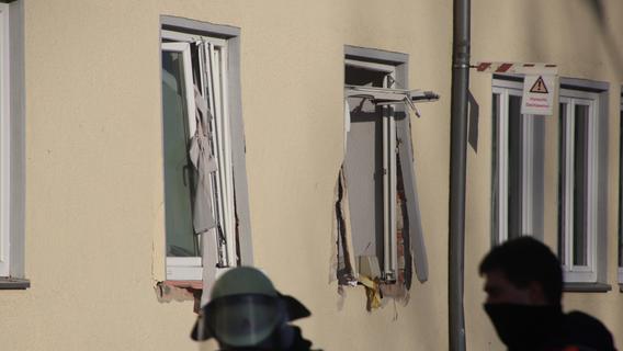 Rettungskräfte gehen an einem Haus entlang, dessen Fenster durch die Explosion zerstört wurden. 