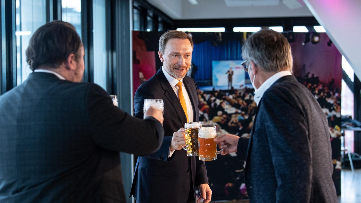 Der FDP-Bundesvorsitzende Christian Lindner (Mitte) stößt beim Politischen Aschermittwoch der Liberalen mit Daniel Föst (links), Landesvorsitzender der FDP in Bayern, und Alexander Muthmann, stellvertretender Vorsitzender der FDP-Landtagsfraktion in Bayern, an