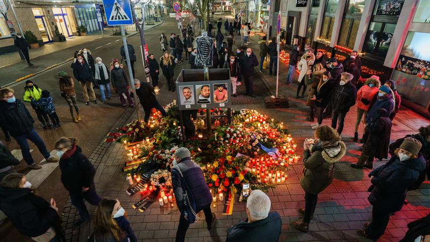 Menschen stehen zur Tatzeit still am Gedenkort am Heumarkt, in der Nähe eines Tatortes. Ein Rechtsextremist hatte in Hanau am 19. Februar 2020 neun Menschen aus rassistischen Motiven erschossen.