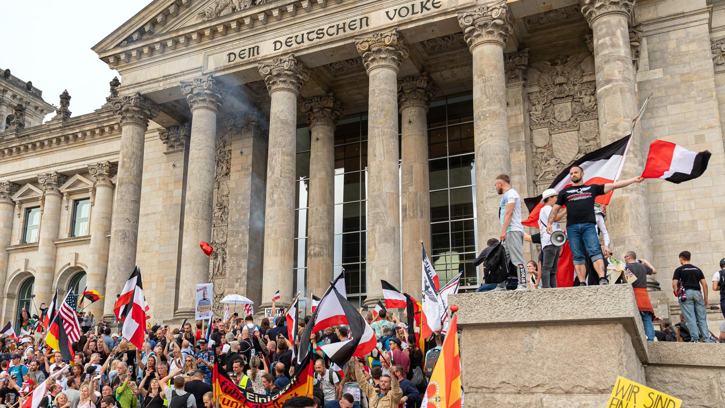 Teilnehmer einer Kundgebung gegen die Corona-Maßnahmen stehen auf den Stufen zum Reichstagsgebäude