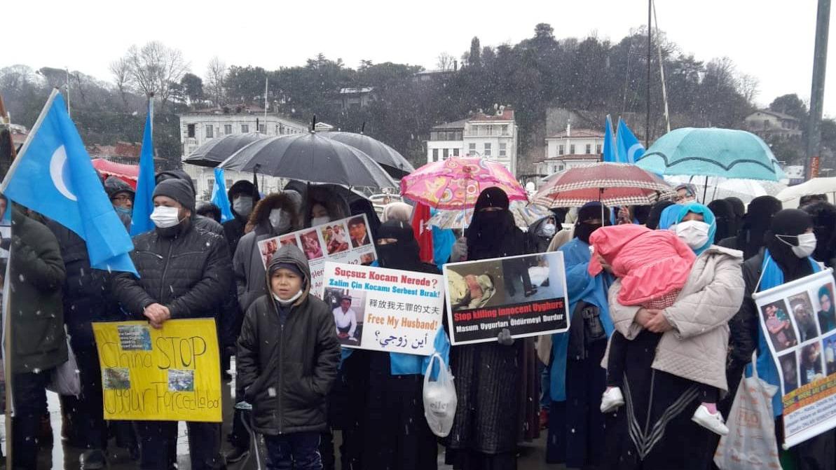 Mitglieder der uigurischen Gemeinschaft, die in der Türkei leben, halten Bilder von vermissten Familienmitgliedern hoch und skandieren "China Stop Genocide".