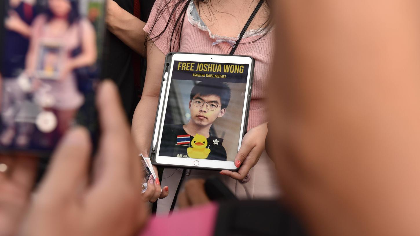 Eine Demonstrantin hält ein Tablet mit einem Bild von Joshua Wong hoch. Der pro-demokratische Aktivist ist ebenfalls unter den Angeklagten und sitzt bereits im Gefängnis.