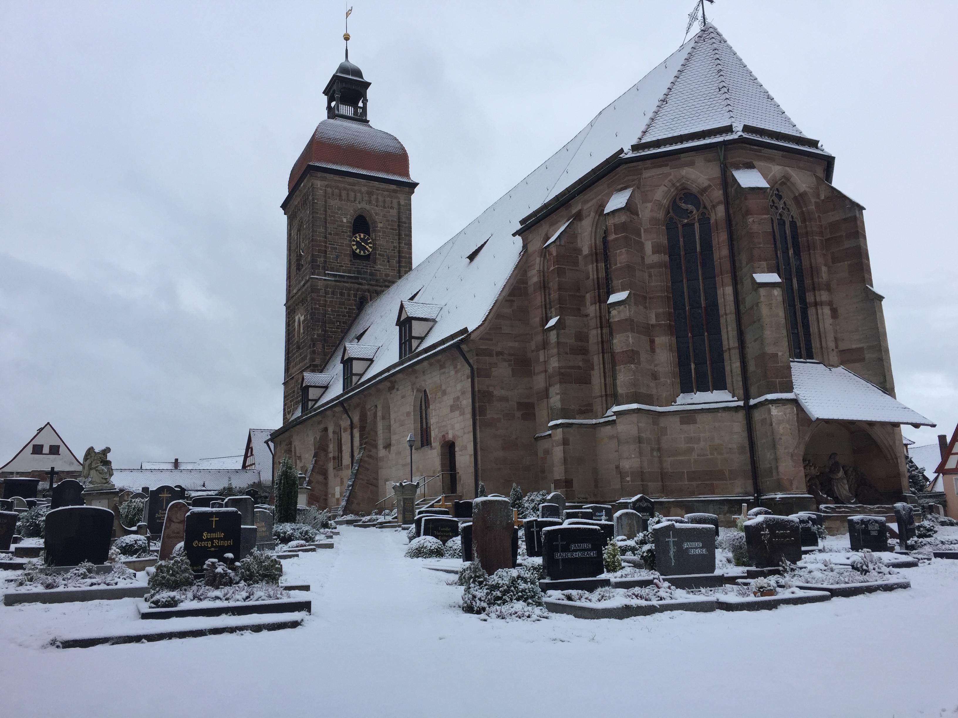 Winter-Stille: Schnee bedeckt die St.Laurentiuskirche in Roßtal und die Gräber des Friedhofs.