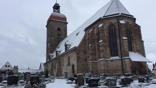 Winter-Stille: Schnee bedeckt die St.Laurentiuskirche in Roßtal und die Gräber des Friedhofs.