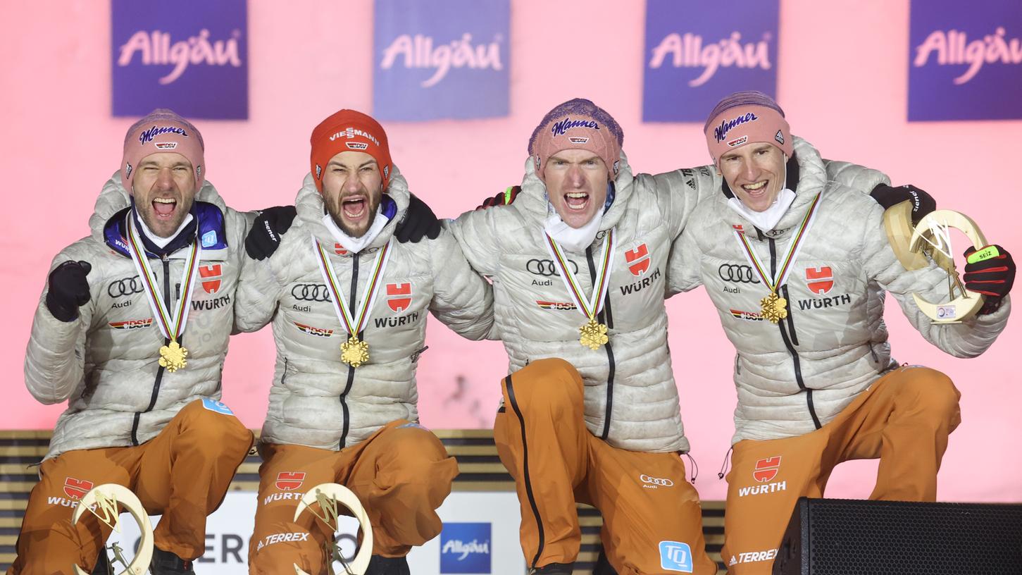 So sehen Sieger aus! Pius Paschke, Markus Eisenbichler, Severin Freund und Karl Geiger jubeln bei bei der Medaillenzeremonie auf der Bühne.