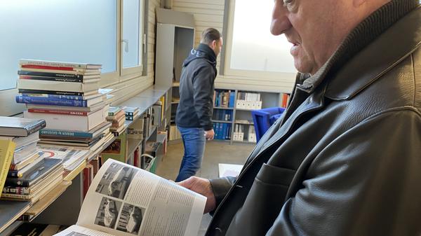 Thomas Sommer blättert in einem Heft über alte Sportwagen. Er sammelt nicht nur Oldtimer, sondern auch alle Informationen, die er dazu finden kann.