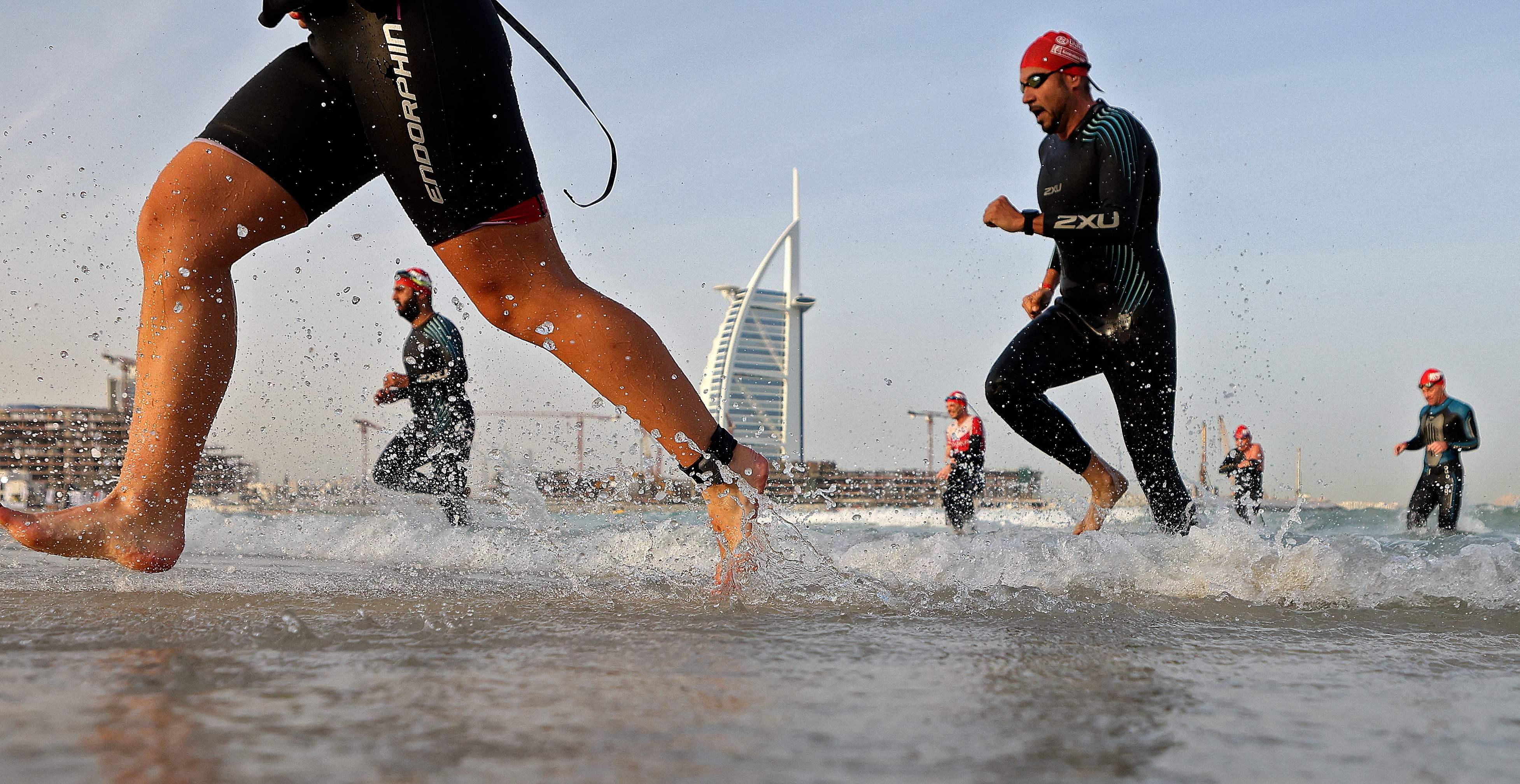 Beim Ironman in Dubai kommen die Schwimmer aus dem Meer zurück - im Hintergrund ein Wahrzeichen des Emirats, das Hotel Burj al Arab.