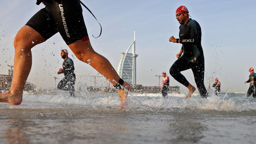 Beim Ironman in Dubai kommen die Schwimmer aus dem Meer zurück - im Hintergrund ein Wahrzeichen des Emirats, das Hotel Burj al Arab.