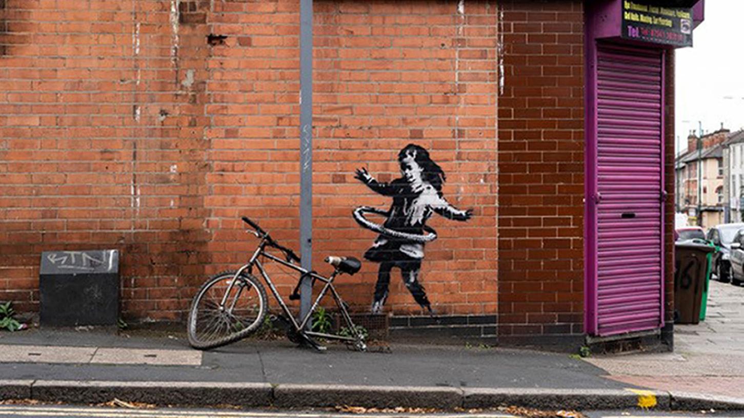Das Banksy-Werk auf einer Backsteinfassade in Nottingham zeigt ein Mädchen, das mit einem Hula Hoop Reifen spielt. Nach vier Monaten wurden es aus der Wand geschnitten und für eine sechsstellige Summe von einem Galeristen gekauft.