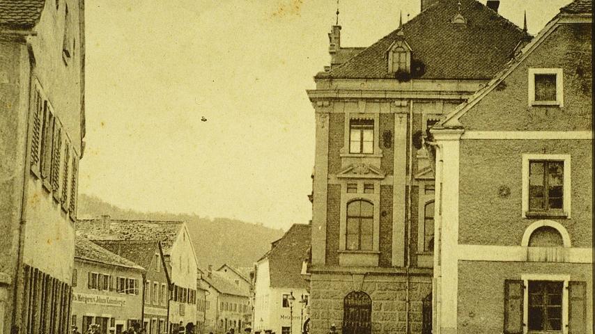 Das Treuchtlinger Rathaus (rechts) zu Beginn des 20. Jahrhunderts. Gut zu sehen sind links im Bild die einstigen Jurahäuser, die auf dem Areal des heutigen Rathausplatzes stehen.
