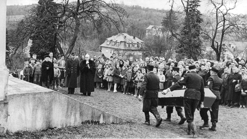 Männer, Frauen und Kinder aus Gräfenberg bilden auf dem Bergfriedhof der Stadt in der Fränkischen Schweiz ein stillschweigendes Spalier für die Opfer der Flugzeug-Katastrophe. Männer der Weißenoher Feuerwehr tragen die Särge in die Aussegnungshalle.