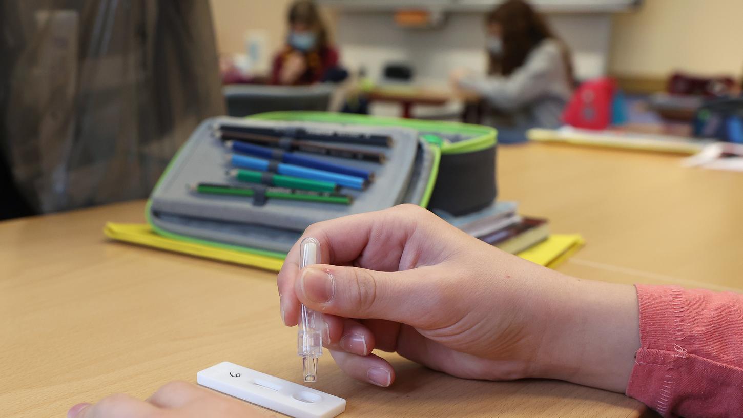 Eine Schülerin träufelt in einem Klassenraum eine Lösung nach einem selbst durchgeführten Corona-Test auf einen Antigentest.