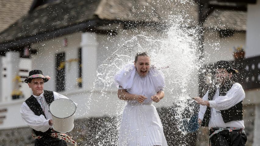 In Trachten gekleidete junge Männer gießen Wasser auf eine junge Frau in dem ungarischen Bergdorf Holloko, das auf der Weltkulturerbe-Liste der Unesco eingetragen ist, während einer Presseveranstaltung. Das Dorf ist berühmt für seine traditionellen Osterfeiern, die aber dieses Jahr wegen der Corona-Pandemie abgesagt werden mussten.