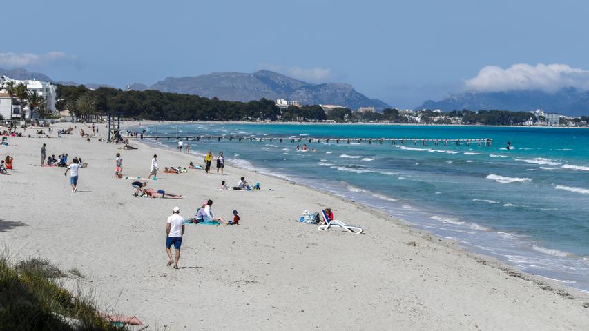 Menschen verbringen ihre Freizeit am Strand. Trotz aller Appelle der Bundesregierung, auf das Reisen angesichts hoher Corona-Zahlen zu verzichten, werden Branchenschätzungen zufolge über Ostern rund 40.000 Deutsche ihren Urlaub auf Mallorca verbringen.