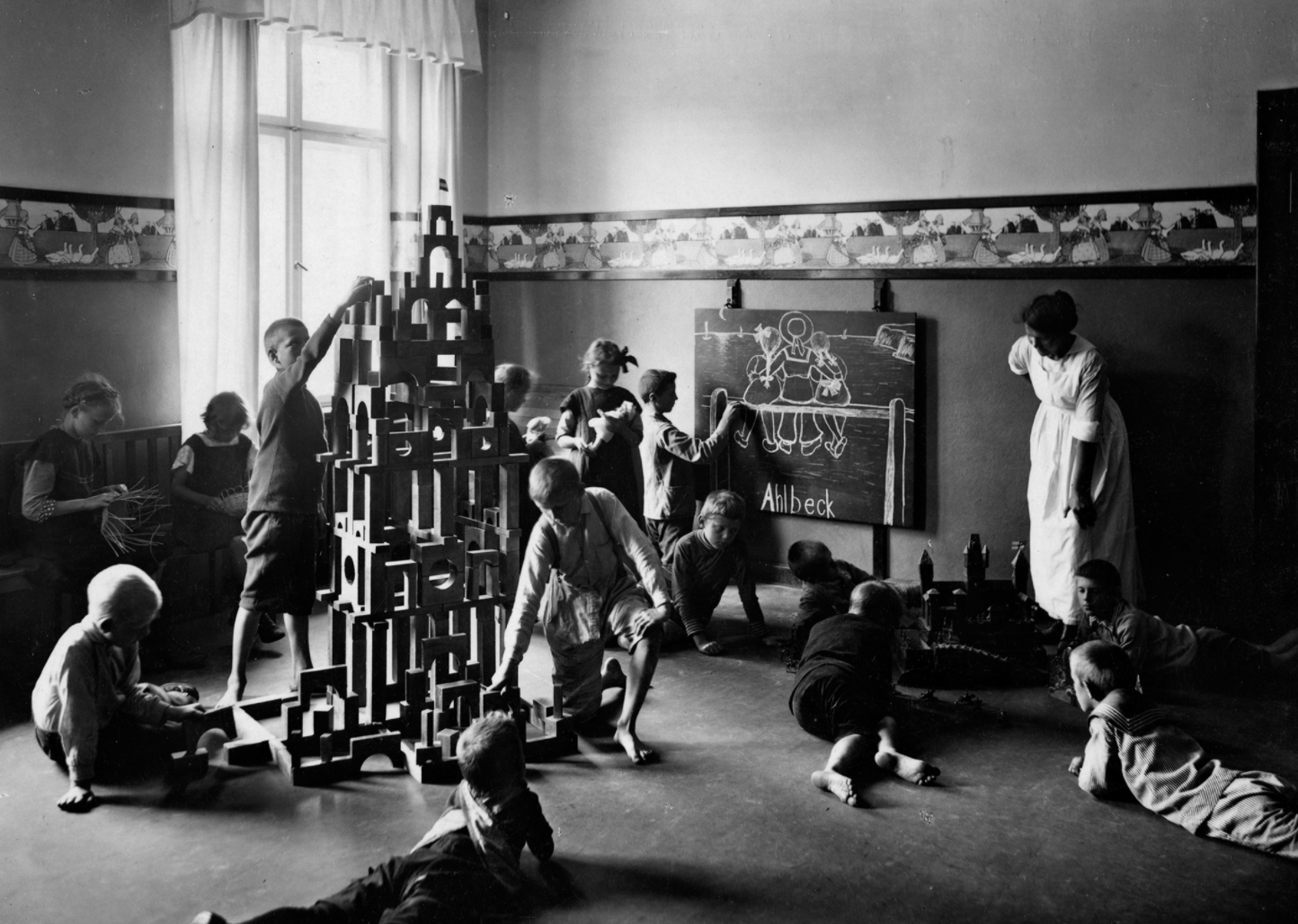 Siemens und ein Kinderheim? Tatsächlich: Das Unternehmen errichtete 1911 und 1912 ein eigenes "Kinderheim" für 150 berufstätige Mütter. Heute würde man die Einrichtung wohl Kindertagesstätte oder Hort nennen. Die Einrichtung  hatte die Unternehmensleitung am 21. März 1911 beschlossen. Das Heim war Anfang April 1912 bezugsfertig, im Oktober 1912 wurde es offiziell eröffnet. Damit war das Unternehmen damals schon modern unterwegs: Die Koexistenz von Familie und Beruf sollte möglich gemacht werden. In der Siemensstadt vermischten sich Arbeit und Privatleben aber ohnehin...