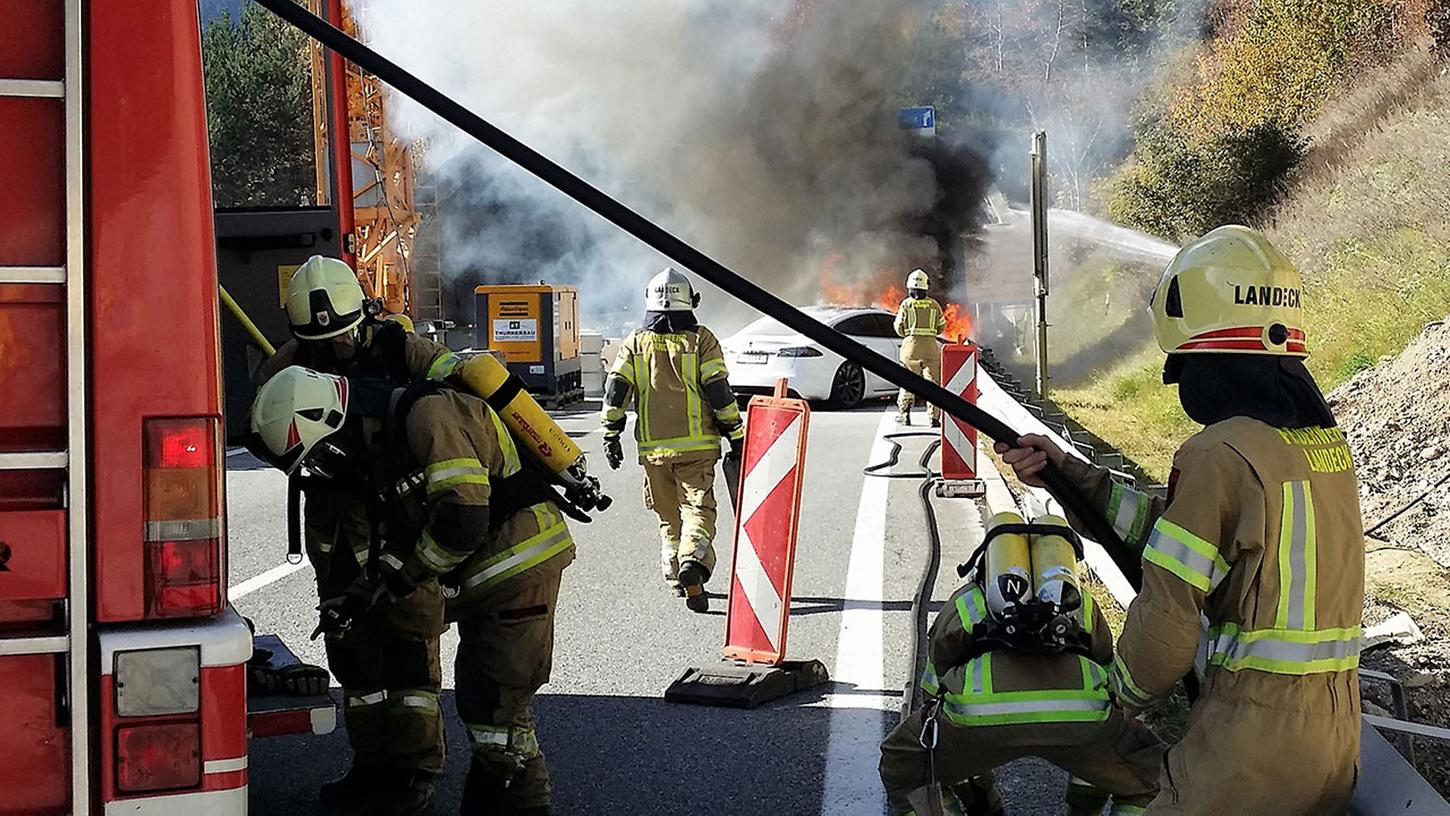 Einsatz mit schwerem Atemschutz und viel Wasser: Einsatzkräfte der Feuerwehr Landeck löschen auf der Arlberg-Autobahn ein in Brand geratenes Elektroauto. Nach einem Unfall kann der Akku des Wagens die Ursache für so ein Feuer sein.