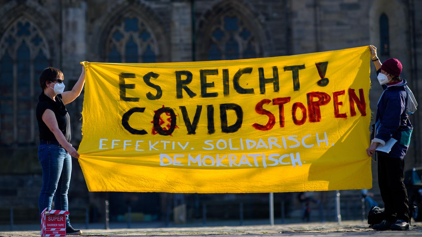 "Es reicht! Covid stoppen Effektiv. Solidarisch. Demokratisch." ist auf einem Tuch zu lesen, das Teilnehmer einer "No-Covid" Kundgebung auf dem Magdeburger Domplatz aufspannen.
