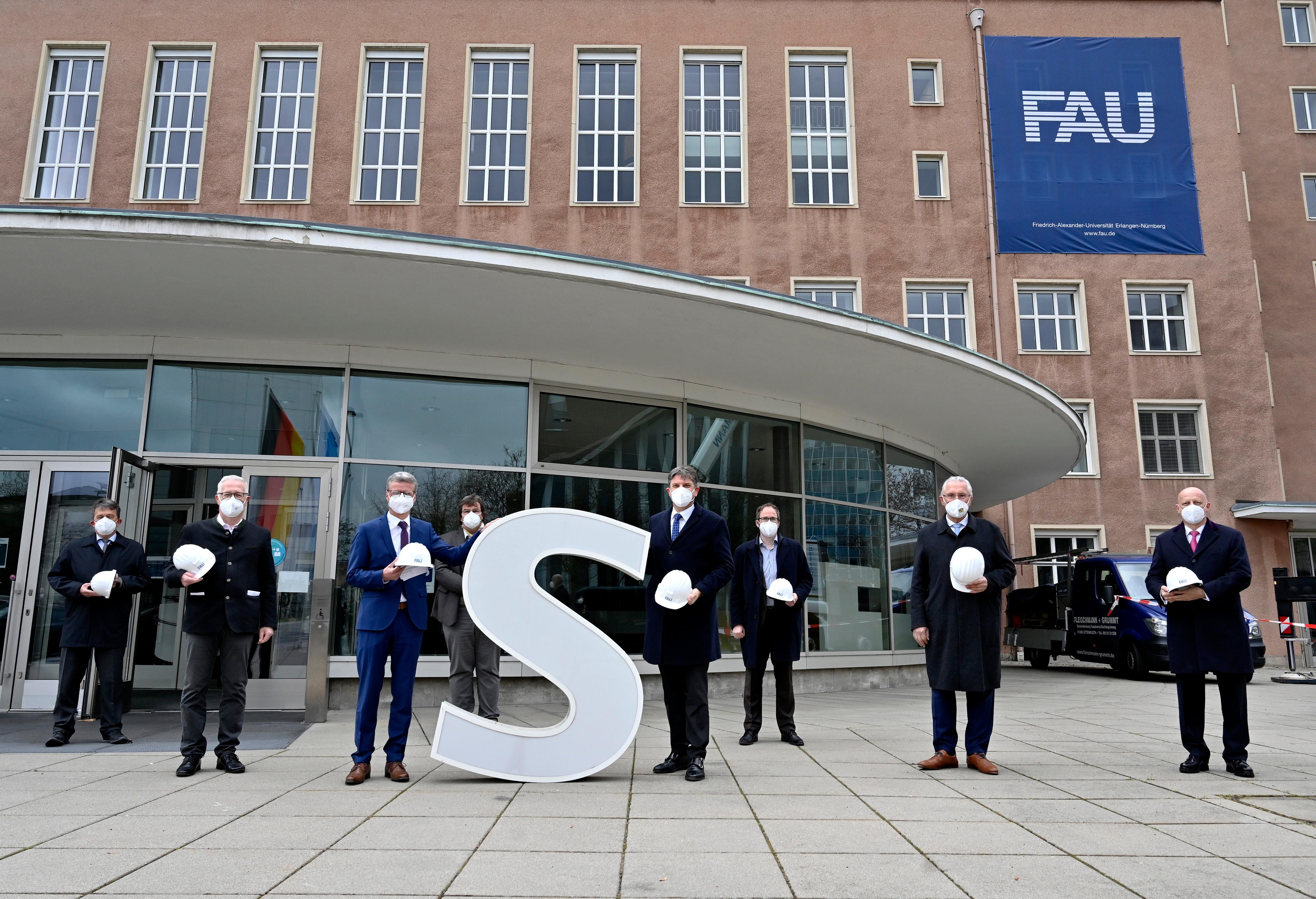 Bereits im Dezember wurden die Schlüssel zum Erlanger „Himbeerpalast“ von der Siemens AG an die FAU übergeben – nun hat die Universität das Gebäude ganz offiziell übernommen. Um die Übergabe auch nach außen hin sichtbar zu markieren, wurde während des Termins symbolisch der erste Buchstabe des Siemens-Schriftzugs vom Gebäude entfernt – in Zukunft ist dann Platz für das FAU-Logo.