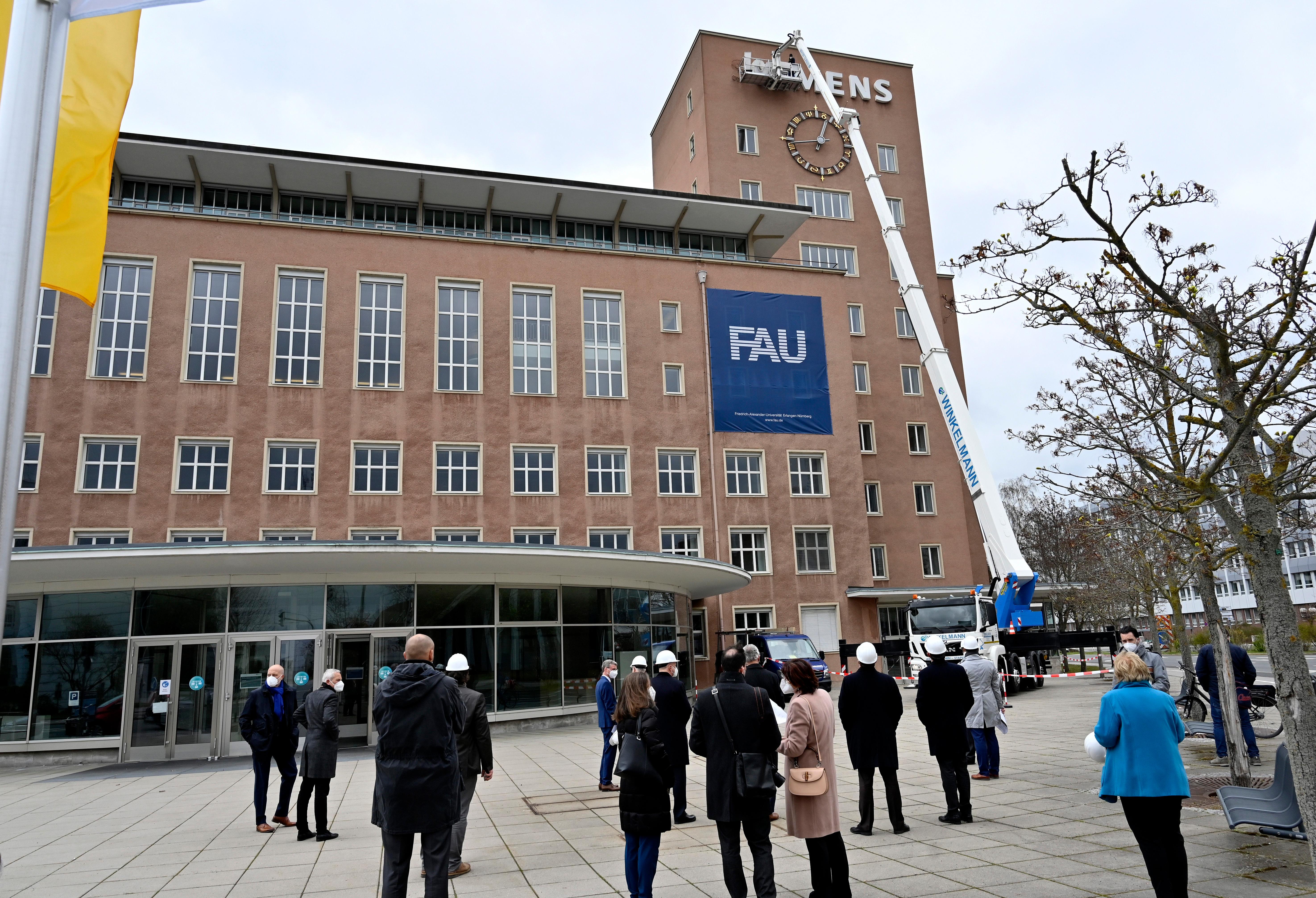 Bereits im Dezember wurden die Schlüssel zum Erlanger „Himbeerpalast“ von der Siemens AG an die FAU übergeben – nun hat die Universität das Gebäude ganz offiziell übernommen. Um die Übergabe auch nach außen hin sichtbar zu markieren, wurde während des Termins symbolisch der erste Buchstabe des Siemens-Schriftzugs vom Gebäude entfernt – in Zukunft ist dann Platz für das FAU-Logo.
