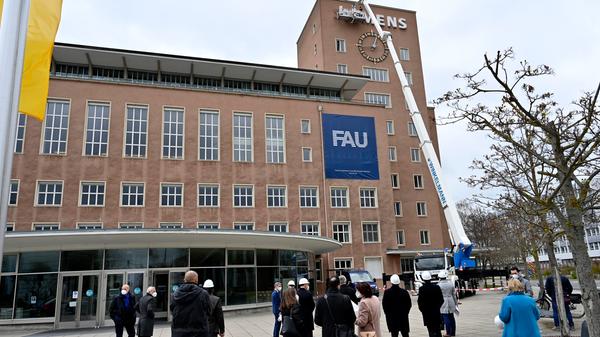 Bereits im Dezember wurden die Schlüssel zum Erlanger „Himbeerpalast“ von der Siemens AG an die FAU übergeben – nun hat die Universität das Gebäude ganz offiziell übernommen. Um die Übergabe auch nach außen hin sichtbar zu markieren, wurde während des Termins symbolisch der erste Buchstabe des Siemens-Schriftzugs vom Gebäude entfernt – in Zukunft ist dann Platz für das FAU-Logo.