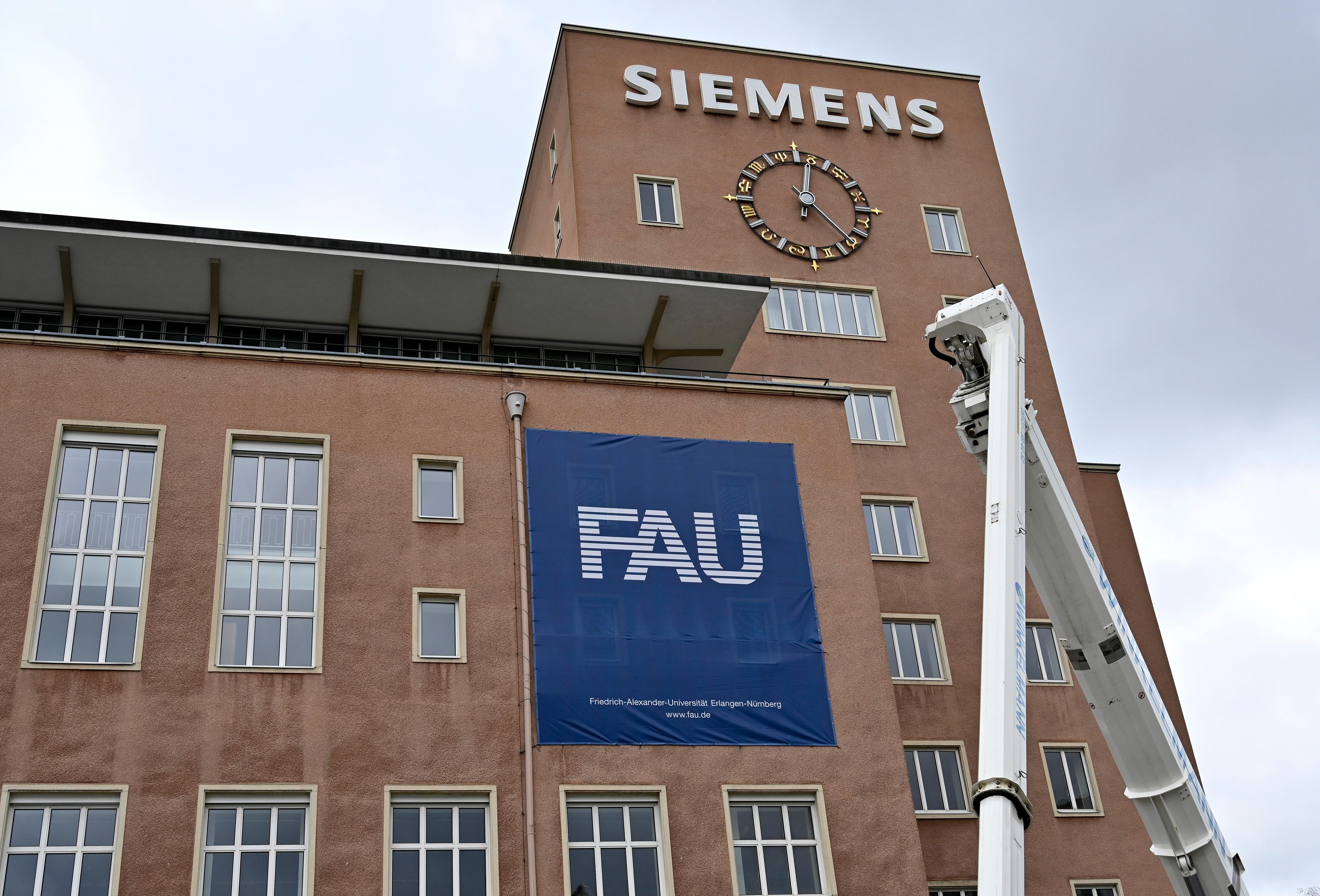 Bereits im Dezember wurden die Schlüssel zum Erlanger „Himbeerpalast“ von der Siemens AG an die FAU übergeben – nun hat die Universität das Gebäude ganz offiziell übernommen. Um die Übergabe auch nach außen hin sichtbar zu markieren, wurde während des Termins symbolisch der erste Buchstabe des Siemens-Schriftzugs vom Gebäude entfernt – in Zukunft ist dann Platz für das FAU-Logo.