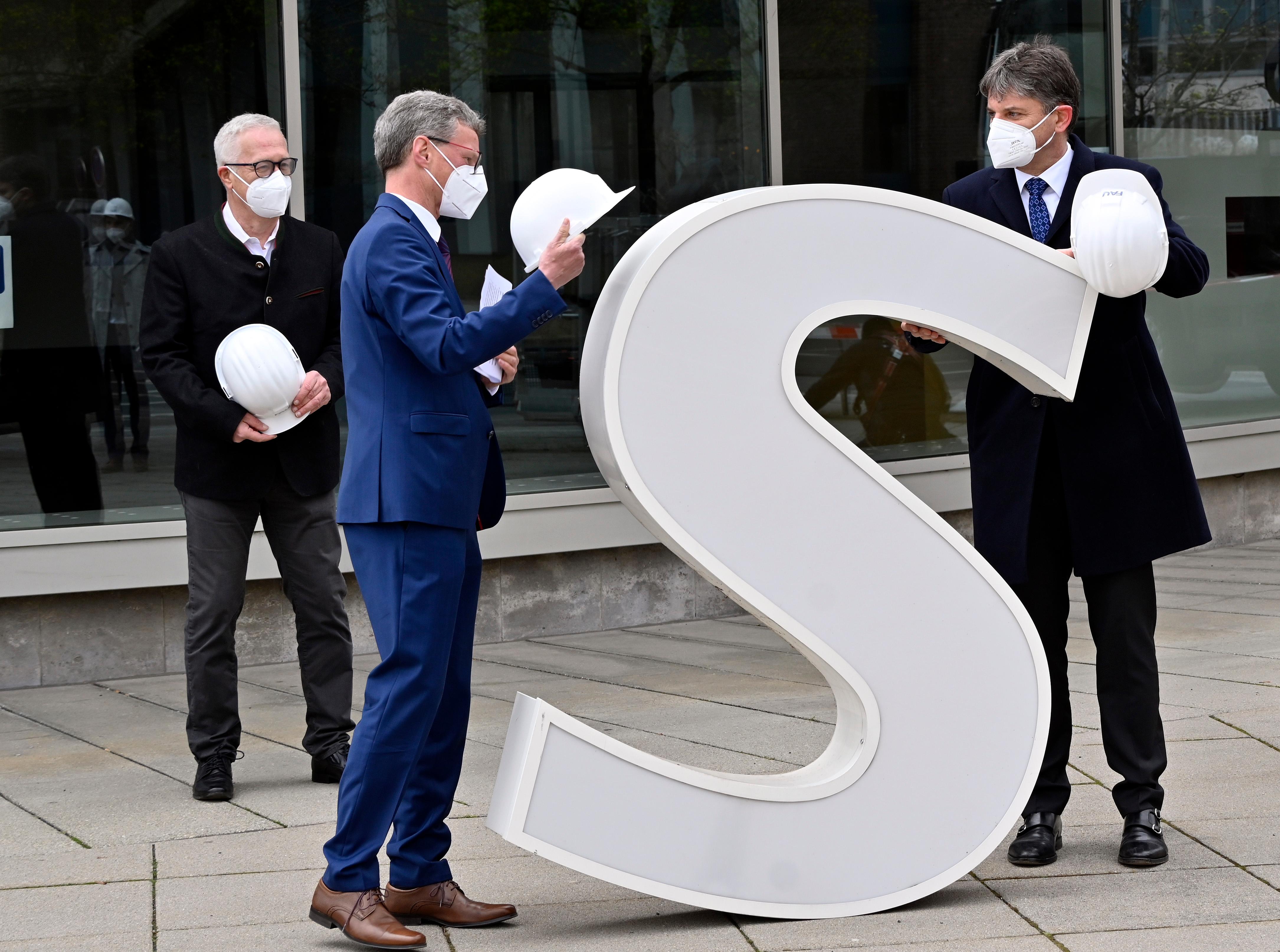 Bereits im Dezember wurden die Schlüssel zum Erlanger „Himbeerpalast“ von der Siemens AG an die FAU übergeben – nun hat die Universität das Gebäude ganz offiziell übernommen. Um die Übergabe auch nach außen hin sichtbar zu markieren, wurde während des Termins symbolisch der erste Buchstabe des Siemens-Schriftzugs vom Gebäude entfernt – in Zukunft ist dann Platz für das FAU-Logo.