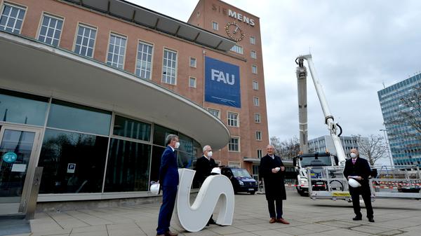 Bereits im Dezember wurden die Schlüssel zum Erlanger „Himbeerpalast“ von der Siemens AG an die FAU übergeben – nun hat die Universität das Gebäude ganz offiziell übernommen. Um die Übergabe auch nach außen hin sichtbar zu markieren, wurde während des Termins symbolisch der erste Buchstabe des Siemens-Schriftzugs vom Gebäude entfernt – in Zukunft ist dann Platz für das FAU-Logo.