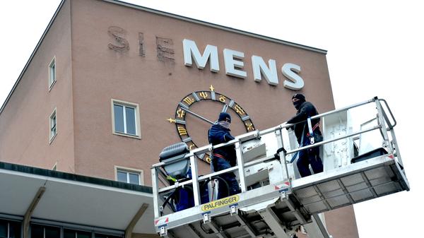 Bereits im Dezember wurden die Schlüssel zum Erlanger „Himbeerpalast“ von der Siemens AG an die FAU übergeben – nun hat die Universität das Gebäude ganz offiziell übernommen. Um die Übergabe auch nach außen hin sichtbar zu markieren, wurde während des Termins symbolisch der erste Buchstabe des Siemens-Schriftzugs vom Gebäude entfernt – in Zukunft ist dann Platz für das FAU-Logo.