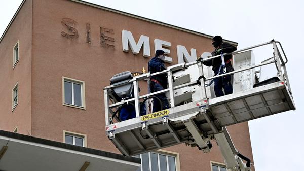Bereits im Dezember wurden die Schlüssel zum Erlanger „Himbeerpalast“ von der Siemens AG an die FAU übergeben – nun hat die Universität das Gebäude ganz offiziell übernommen. Um die Übergabe auch nach außen hin sichtbar zu markieren, wurde während des Termins symbolisch der erste Buchstabe des Siemens-Schriftzugs vom Gebäude entfernt – in Zukunft ist dann Platz für das FAU-Logo.