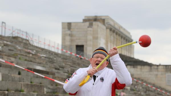 Auch mit 80 Jahren ist Dietmar Keller noch topfit. Er stößt die Kugel, wirft den Hammer (hier vor der Nürnberger Steintribüne) oder den Speer und unterstützt seinen Bekannten Achim Sanftleben mit seiner jahrzehntelangen Erfahrung als Trainer. Die beiden fahren "gemeinsam zu nationalen, internationalen Meisterschaften und wollen bei unseren Reisen nach Polen, Ungarn, Spanien, Österreich usw. noch ein wenig von unserem arbeitsreichen Leben mit Lebensfreude ausklingen lassen".