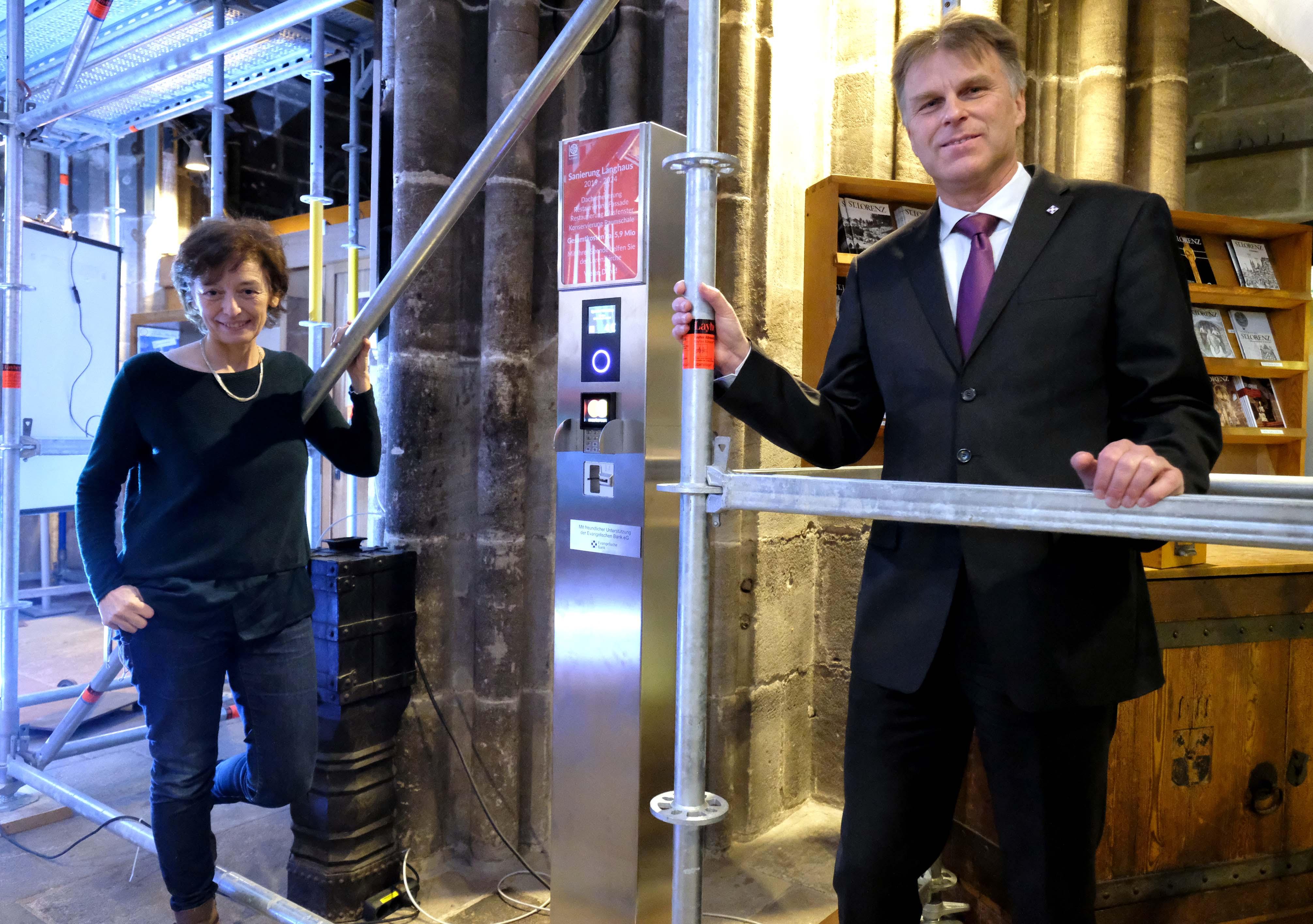 Pfarrerin Claudia Voigt-Grabenstein und Günter Stibbe von der Evangelischen Volksbank stellen die digitale Spendensäule am Eingang der Lorenzkirche vor.