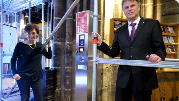 Pfarrerin Claudia Voigt-Grabenstein und Günter Stibbe von der Evangelischen Volksbank stellen die digitale Spendensäule am Eingang der Lorenzkirche vor.