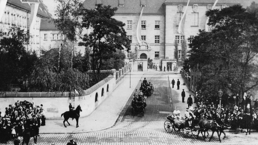 Am 11. September 1916 kam Ludwig III. zur Einweihung des Justizgebäudes. Hier verlässt der König von Bayern in einer offenen Kutsche das Justizgebäude an der mit vielen Bäumen gesäumten Fürther Straße. Hinter Absperrketten winken ihm die Nürnberger zu.  