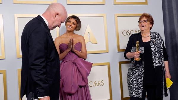 Donald Graham Burt (l), Artdirector, und Jan Pascale (r), Szenenbildnerin, posieren im Presseraum mit dem Oscar für das beste Produktionsdesign für "Mank" mit Schauspielerin Halle Berry.