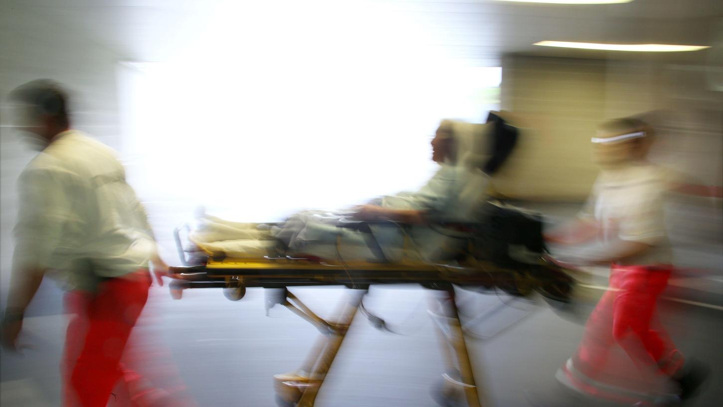 Rettungsassistenten liefern eine Notfallpatientin auf einer Trage in ein Krankenhaus ein.