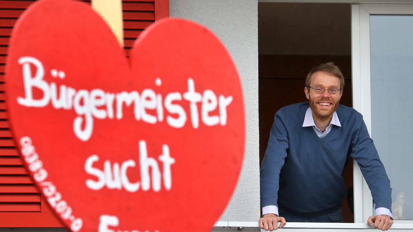 Jörg Aghte, Bürgermeister der Gemeinde Sigmarszell, schaut aus dem Fenster seines Rathauses. Im Vordergrund ist das Herz des Maibaums zu sehen.