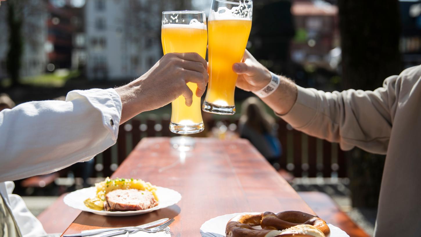 Zwei Menschen sitzen bei gutem Wetter in einem Biergarten und stoßen mit einem Bier an. (Zu dpa «Kretschmann macht Hoffnung auf geöffnete Biergärten zu Pfingsten») +++ dpa-Bildfunk +++ Zwei Menschen sitzen bei gutem Wetter in einem Biergarten und stoßen mit einem Bier an. (Zu dpa «Kretschmann macht Hoffnung auf geöffnete Biergärten zu Pfingsten») +++ dpa-Bildfunk +++
