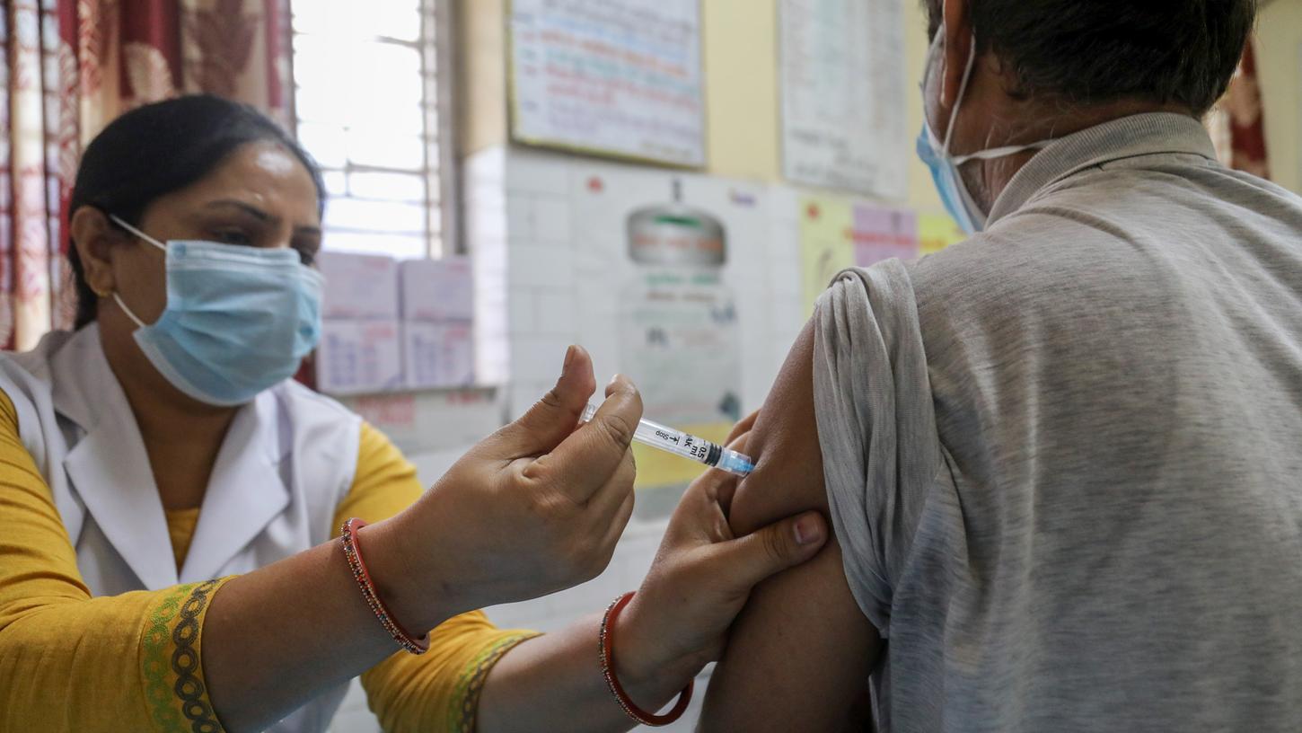 Eine Mitarbeiterin des Gesundheitswesens injiziert einem Mann eine Dosis des Corona-Impfstoffs des indischen Herstellers Bharat Biotech.