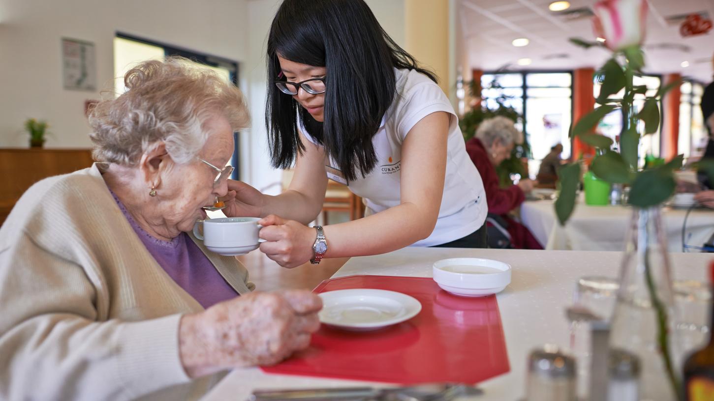 Eine Altenpflegerin hilft einer Heimbewohnerin beim Mittagessen.