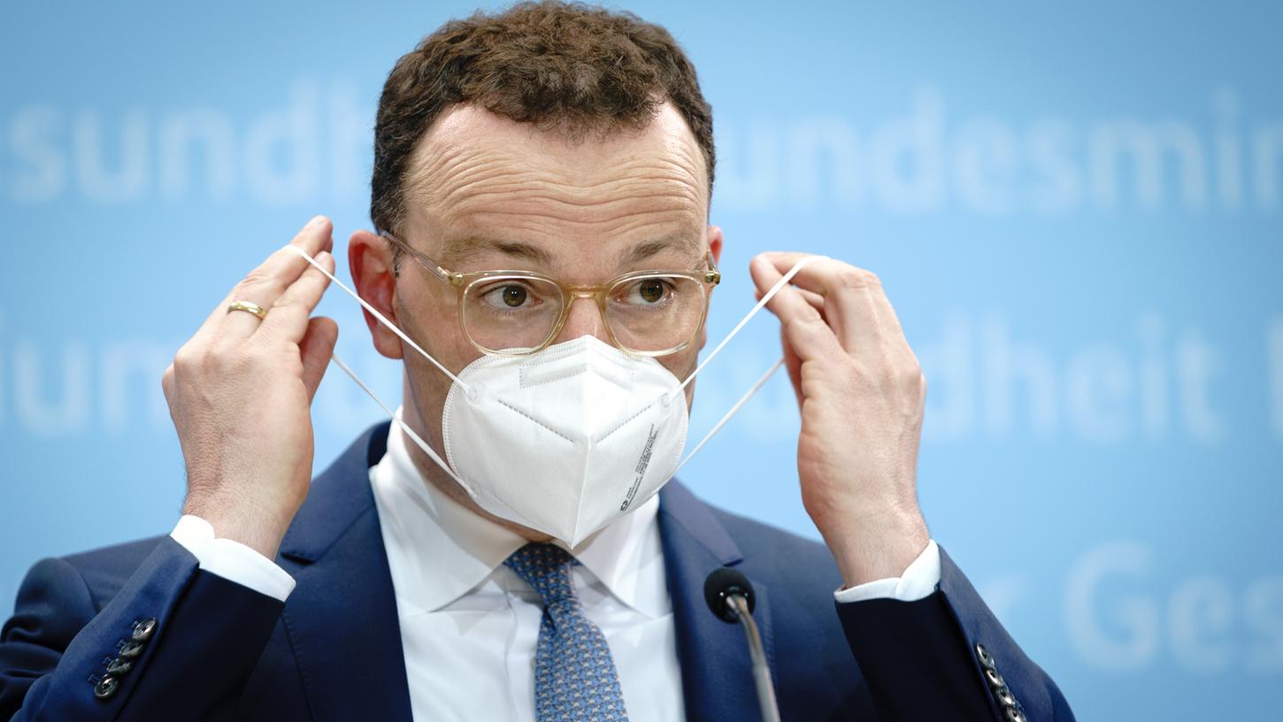Jens Spahn (CDU), Bundesminister für Gesundheit, setzt zum Ende der Pressekonferenz in seinem Ministerium die Mund-Nasenbedeckung auf.