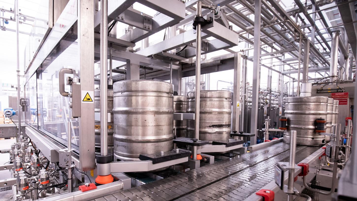  Bierfässer stehen in der Kontroll- und Reinigungsanlage einer Produktionsstätte. 