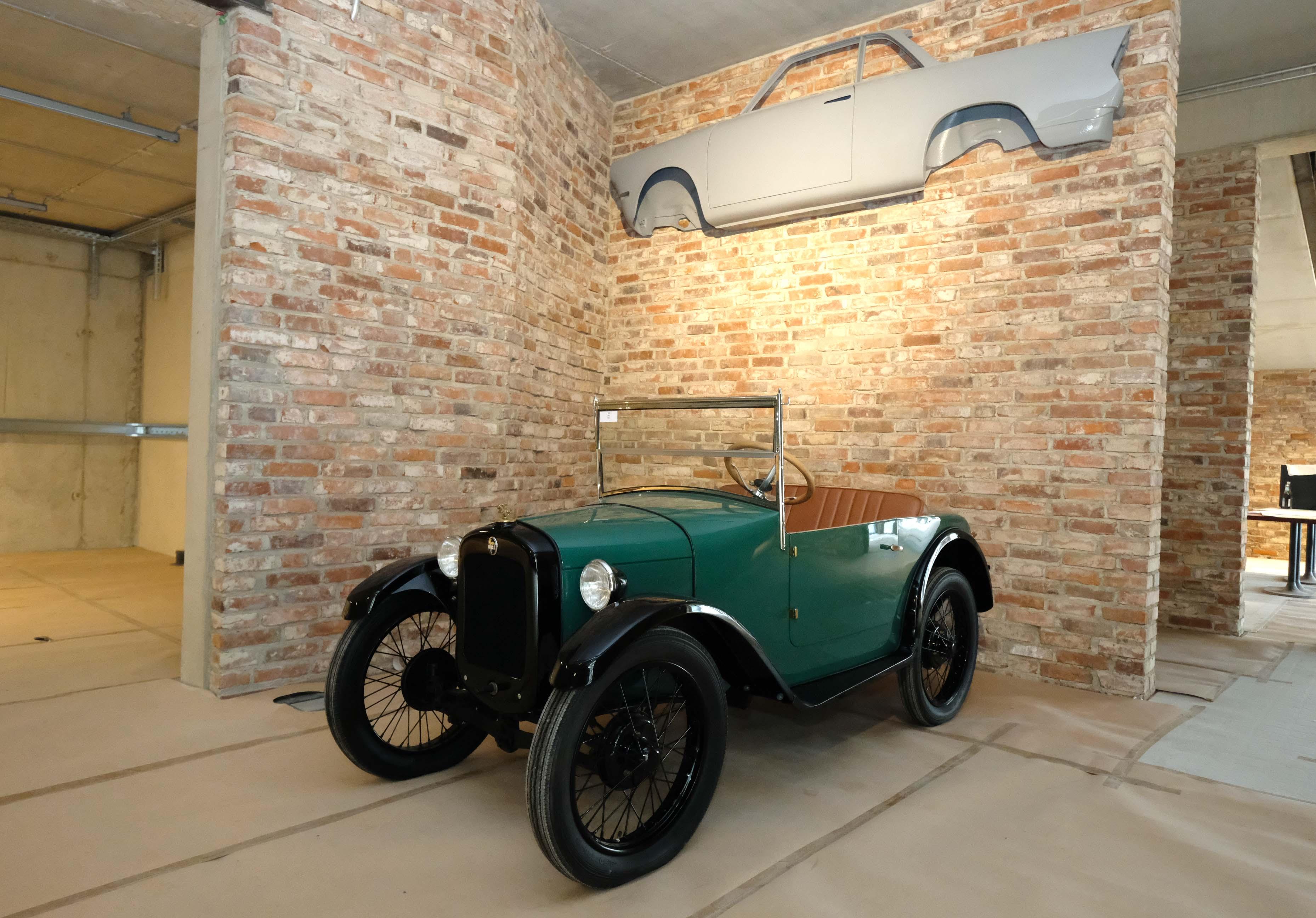 Ein zweisitziges Cabrio aus dem Jahr 1928/29. Präsentiert wird es vor einer Wand aus alten Steinen. 