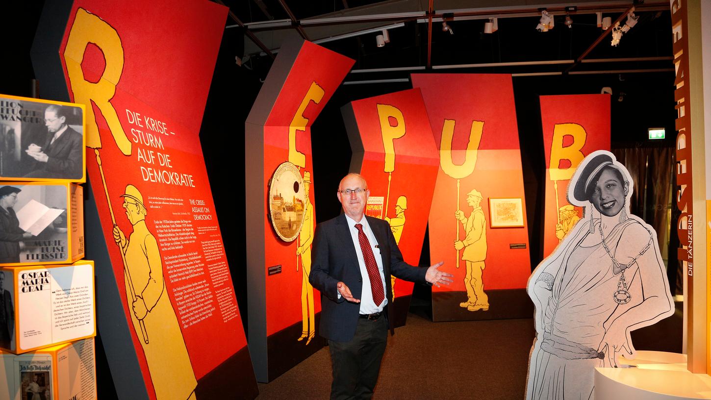 Ausstellungskurator Wolfgang Jahn vom Haus der Bayerischen Geschichte im abschließenden Ausstellungsteil, der dem politischen Ringen um die Weimarer Republik gewidmet ist. Die Würfel links erinnern an die wichtigen Schriftstellerinnen und Schriftsteller (von oben) Lion Feuchtwanger, Marie-Luise Fleißer, Oskar Maria Graf, Hedwig Courths-Mahler und Ödön von Horvath. Rechts die Silhouette von Josephine Baker. Ausstellungskurator Wolfgang Jahn vom Haus der Bayerischen Geschichte im abschließenden Ausstellungsteil, der dem politischen Ringen um die Weimarer Republik gewidmet ist. Die Würfel links erinnern an die wichtigen Schriftstellerinnen und Schriftsteller (von oben) Lion Feuchtwanger, Marie-Luise Fleißer, Oskar Maria Graf, Hedwig Courths-Mahler und Ödön von Horvath. Rechts die Silhouette von Josephine Baker.