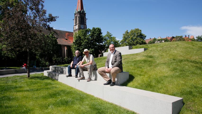 Bürgermeister Christian Vogel, Heinz-Claude Aemmer vom Bürgerverein Gostenhof und Pfarrer Peter Bielmeier von der Dreieinigkeitskirche (von rechts nach links) testen die neuen Sitzgelegenheiten in der frisch sanierten Veit-Stoß-Anlage.