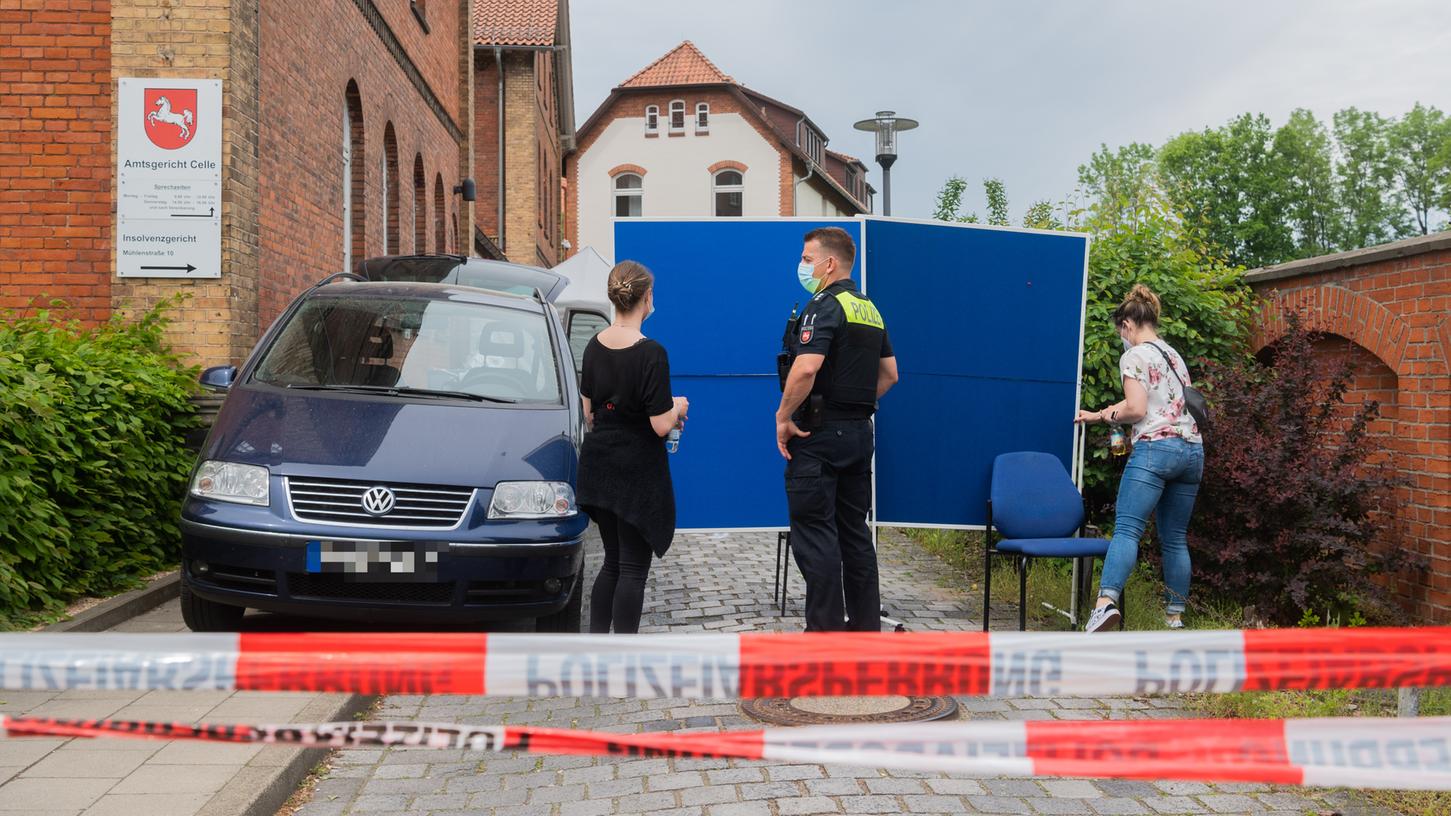 Polizisten stehen im Eingangsbereich des Amtsgerichts Celle, der durch blaue Tafel verdeckt wird. Auf dem Gelände des Amtsgerichts hat ein Mann eine Frau und anschließend sich selbst erschossen. 