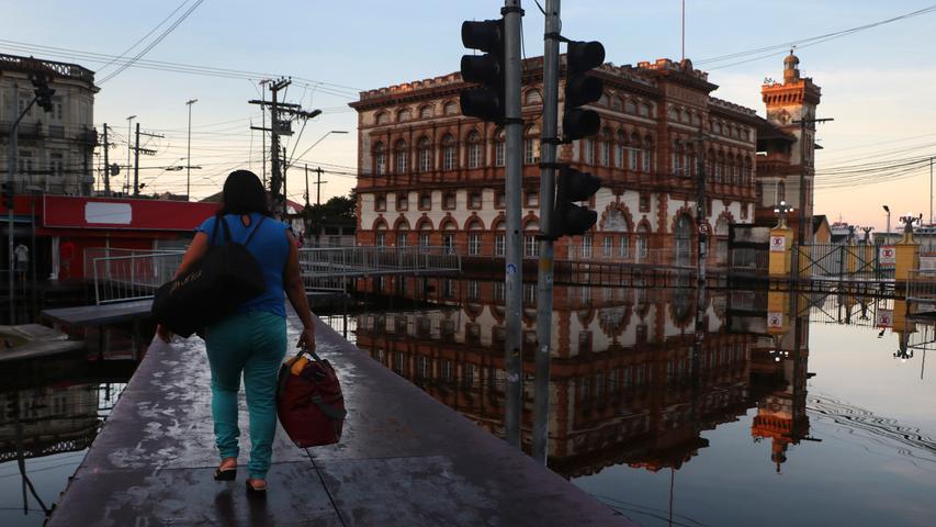 In Brasilien gibt es andere Probleme: Die Flüsse rund um die Stadt Manaus sind auf ein Niveau angeschwollen, das seit mehr als einem Jahrhundert der Aufzeichnungen nicht mehr erreicht wurde. Eine Frau nutzt den hölzernen Steg, der die überschwemmte Straße ersetzen muss.