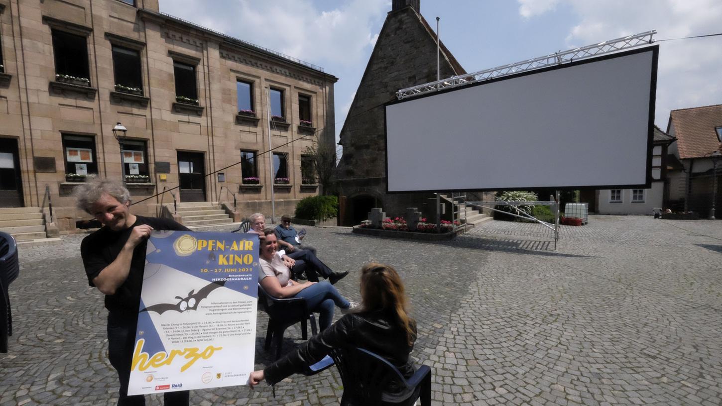 Wolfgang Meyer von mobileskino.de zeigt das neue Open-Air-Kinoplakat. Die Leinwand ist schon aufgebaut.